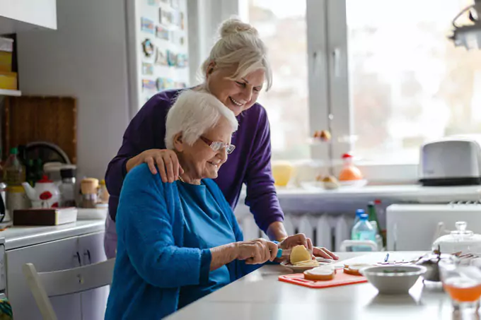 Unterstützung im Alltag: Seniorin beim gemeinsamen Zubereiten von Mahlzeiten mit einfühlsamer Alltagshilfe / Pflegerin in Dreieich